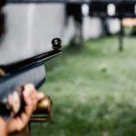 Ljudska ruka drži pušku ciljajući metu (discipline u streljaštvu)